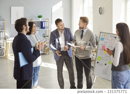 Cheerful business professionals discussing ideas and analyzing plans during team meeting in office. 131375771