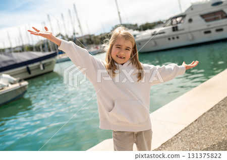Girl standing with arms outstretched on sunny pier Girl standing with arms outstretched on sunny pier 131375822