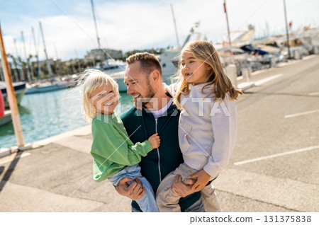 Father embracing children on sunny marina pier 131375838