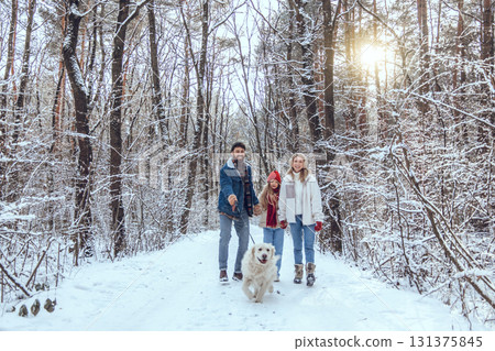 Parents and their daughter walking with a dog in a snowy forest 131375845