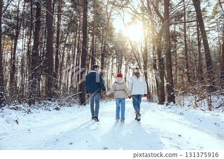 Family having a walk in a winter forest while holding hands 131375916