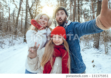 Cute young family enjoying and having fun in a winter forest Cute young family enjoying and having fun in a winter forest 131375951