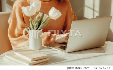 Woman freelance working on laptop with coffee and tulips, minimalist style, warm tones 131376744
