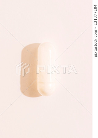 Single white capsule macro with strong side shadow on pastel background healthcare supplement concept Single white capsule macro with strong side shadow on pastel background healthcare supplement concept 131377194
