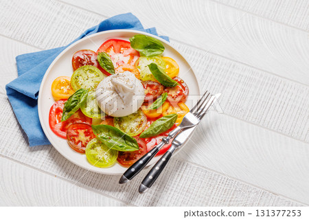 Fresh burrata served on slices of colorful tomatoes Fresh burrata served on slices of colorful tomatoes 131377253