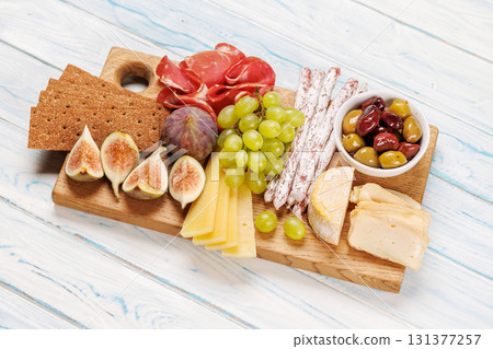 Antipasto platter with prosciutto, cheese, olives, salami, figs, grapes, and crackers 131377257