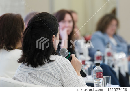 Woman speaking into microphone during panel discussion at professional event 131377458