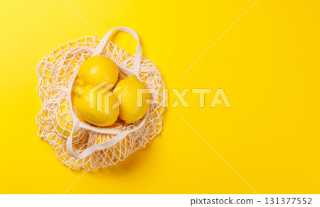 Fresh juicy lemons in a mesh bag, flat lay style 131377552