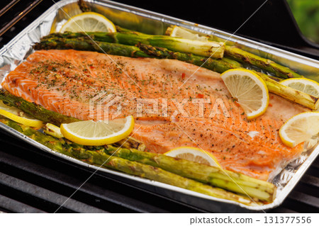 Grilled salmon fillets and asparagus sizzling on a barbecue grill Grilled salmon fillets and asparagus sizzling on a barbecue grill 131377556