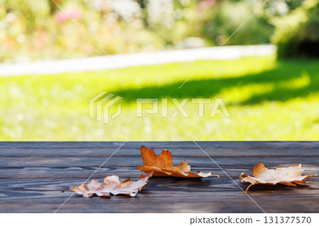 Wooden table with autumn leaves and sunny bokeh background 131377570