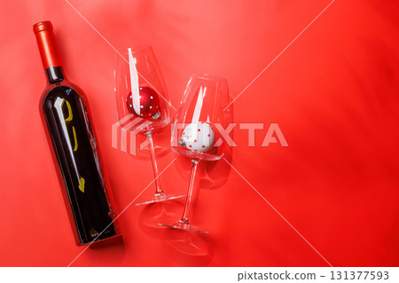 Wine glasses with Christmas baubles inside and wine bottle on red background Wine glasses with Christmas baubles inside and wine bottle on red background 131377593