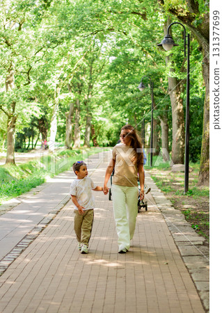 Caucasian mother and son enjoy leisure time in park walking and talking, smiling laughing. Serene family connection. 131377699