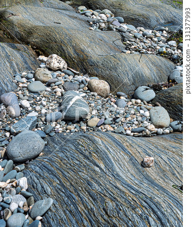 The scene shows large, smooth rocks and smaller pebbles on the shoreline. The exposed rocks display interesting textures near the ocean in West Cork. The scene shows large, smooth rocks and smaller pebbles on the shoreline. The exposed rocks display interesting textures near the ocean in West Cork. 131377993