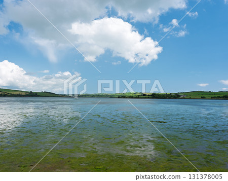 A serene, wide river under a bright, cloudy sky. 131378005