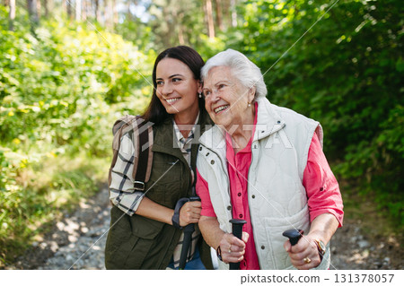 Senior woman and daughter enjoying hike with trekking poles. Senior woman and daughter enjoying hike with trekking poles. 131378057