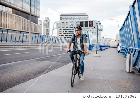 City commuter riding bike on street, wearing backpack. 131378062