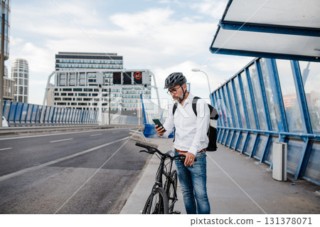 City commuter riding bike from work, reading text message on phone. City commuter riding bike from work, reading text message on phone. 131378071