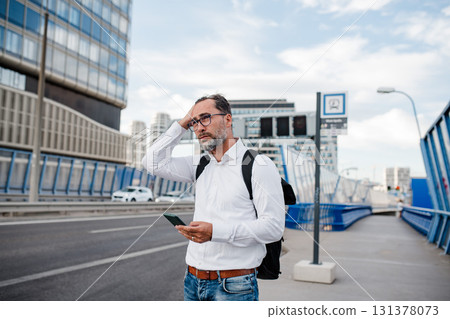 Mature businessman walking home from work, texting on smartphone. 131378073