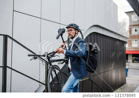 City commuter carrying bicycle up urban stairs. 131378095