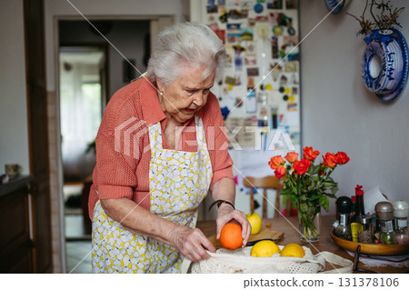 Senior lady in apron preparing fresh fruit at home. 131378106
