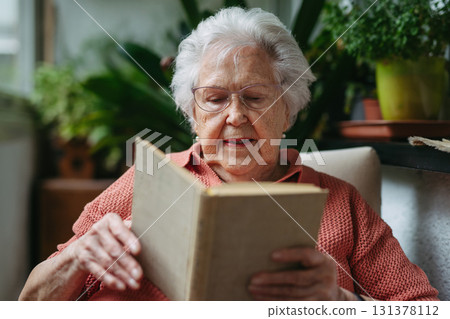 Senior lady sitting at balcony, reading book. 131378112