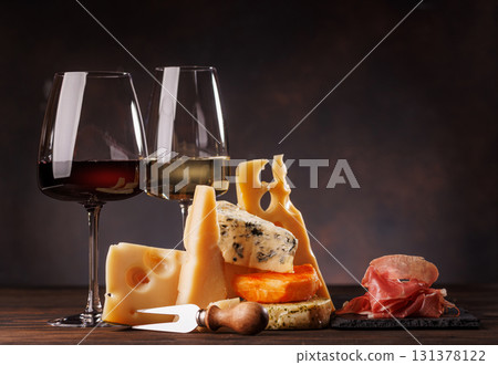 Assorted cheeses paired with glasses of wine on a rustic table 131378122