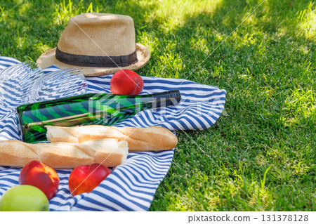 Picnic with wine, fruits, and baguette on a green meadow Picnic with wine, fruits, and baguette on a green meadow 131378128