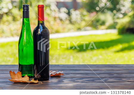 Wine bottles on a wooden table, glowing with sunny bokeh in the background Wine bottles on a wooden table, glowing with sunny bokeh in the background 131378140