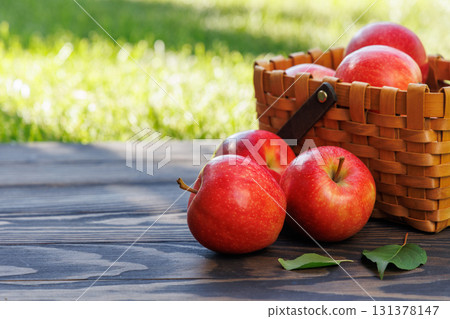 Basket of ripe red apples on a wooden table 131378147