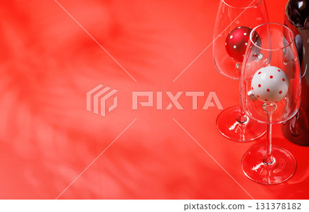 Wine glasses with Christmas baubles inside on red background, mockup for holiday card or invitation Wine glasses with Christmas baubles inside on red background, mockup for holiday card or invitation 131378182