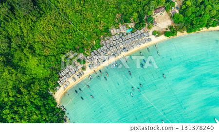A stunning aerial view of a tropical beach village with rows of small huts along the coastline, 131378240