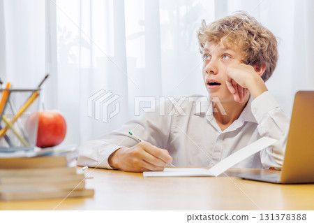 Schoolboy studying at home, doing homework 131378388