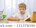 Schoolboy sitting at home, with focus and concentration while doing homework 131378390