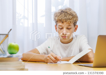 Schoolboy sitting at home, with focus and concentration while doing homework 131378390