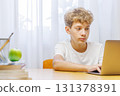 Schoolboy studying online at home with a laptop 131378391