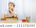 Schoolboy studying at home with notebook, and learning materials 131378395