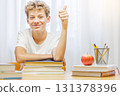 Schoolboy studying at home with notebook, and learning materials, smiling happily 131378396