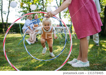 Family enjoying outdoor summer gathering with playful activities. 131378405
