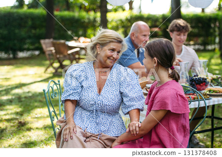 Grandmother talking with granddaughter at family garden party. Grandmother talking with granddaughter at family garden party. 131378408