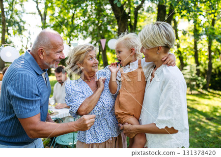 Smiling senior couple with grandchild and daughter at family gathering. Smiling senior couple with grandchild and daughter at family gathering. 131378420