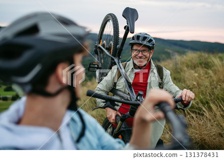 Older couple cycling together in nature, smiling and enjoying outdoor adventure. 131378431