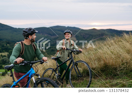 Couple cycling together in nature, smiling and enjoying outdoor adventure. Couple cycling together in nature, smiling and enjoying outdoor adventure. 131378432