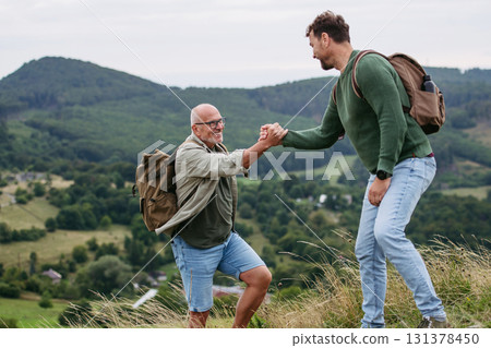 Adult son and older father hiking togeter in nature. Adult son and older father hiking togeter in nature. 131378450