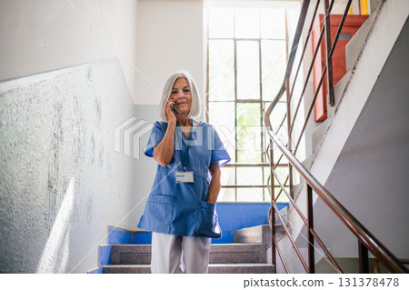 Tired nurse taking break during hospital shift, calling with family. 131378478