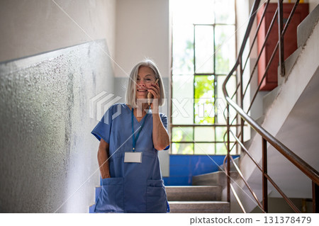 Tired nurse taking break during hospital shift, calling with family. 131378479