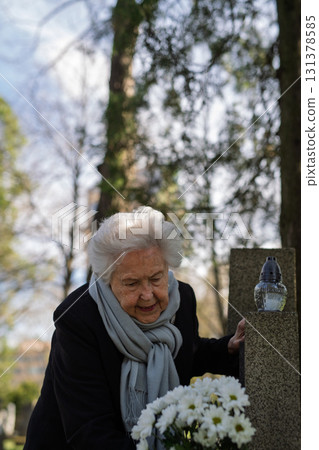 Elderly woman visiting a grave on All Saints Day. Elderly woman visiting a grave on All Saints Day. 131378585