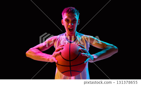Basketball player screaming with ball in neon lights showing raw emotion 131378655