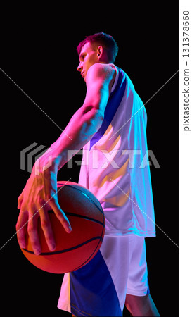 Basketball player holding ball in neon light with determination and strength 131378660