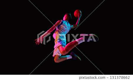 Basketball player soaring with ball in neon lights showing athletic power 131378662