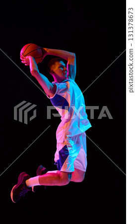 Basketball player performing dramatic dunk with neon glow and fierce expression Basketball player performing dramatic dunk with neon glow and fierce expression 131378673